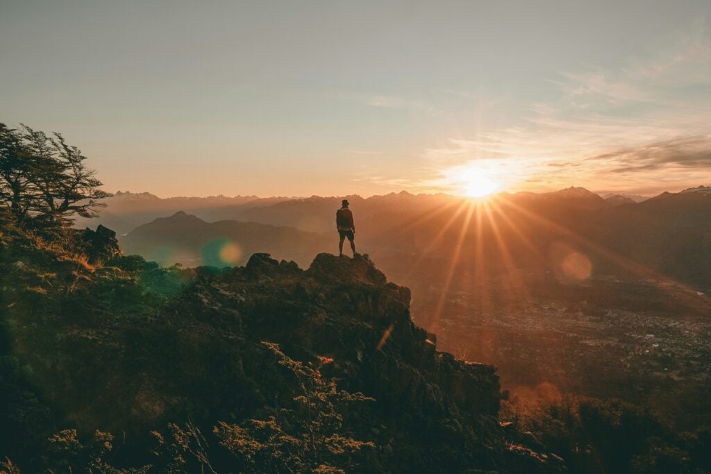 Person standing on mountain peak during sunset at Confluence Behavioral Health.