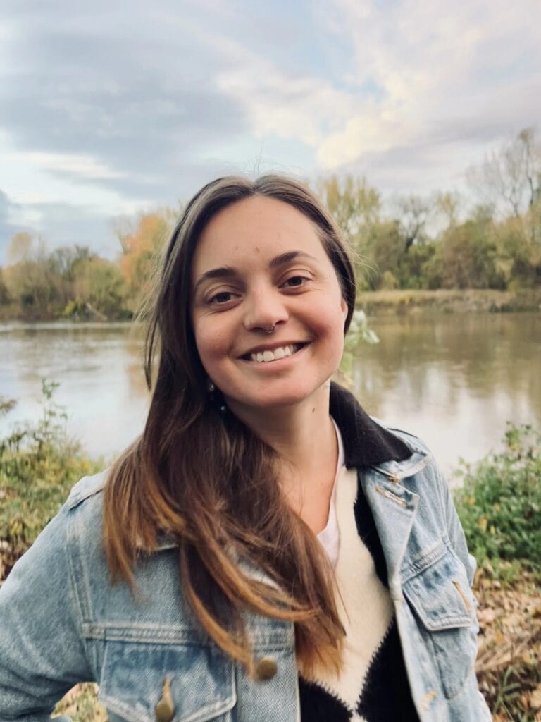 Young woman smiling outdoors near river.