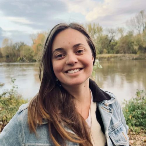 Young woman smiling outdoors near river.