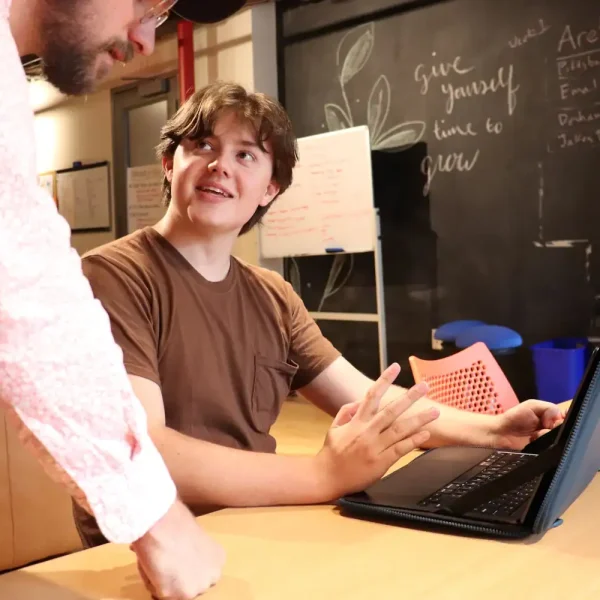 Young man receiving guidance in a supportive transitional living environment.