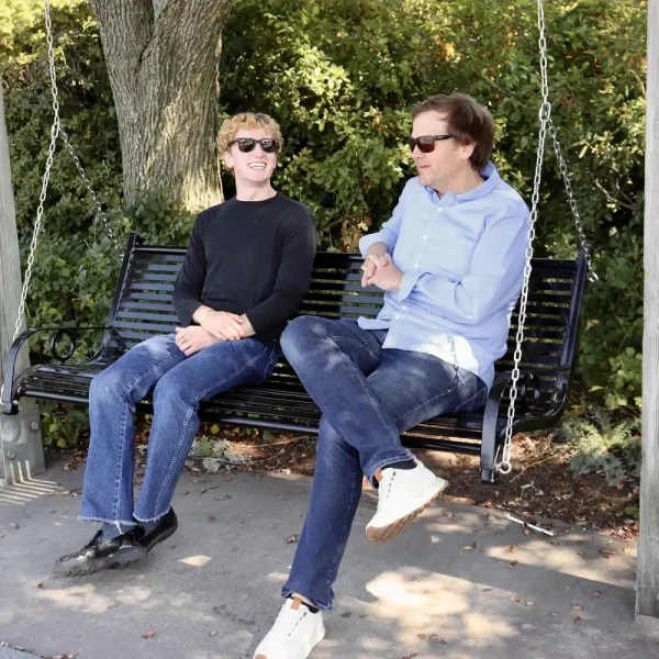 Two people sitting on a swing at a transitional living center, engaging in conversation.